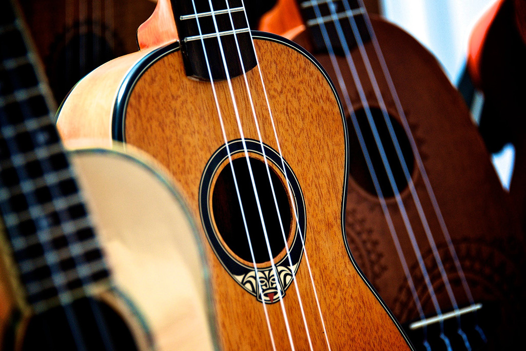 Tre olika stränginstrument av gitarrtyp står uppställda, bild.